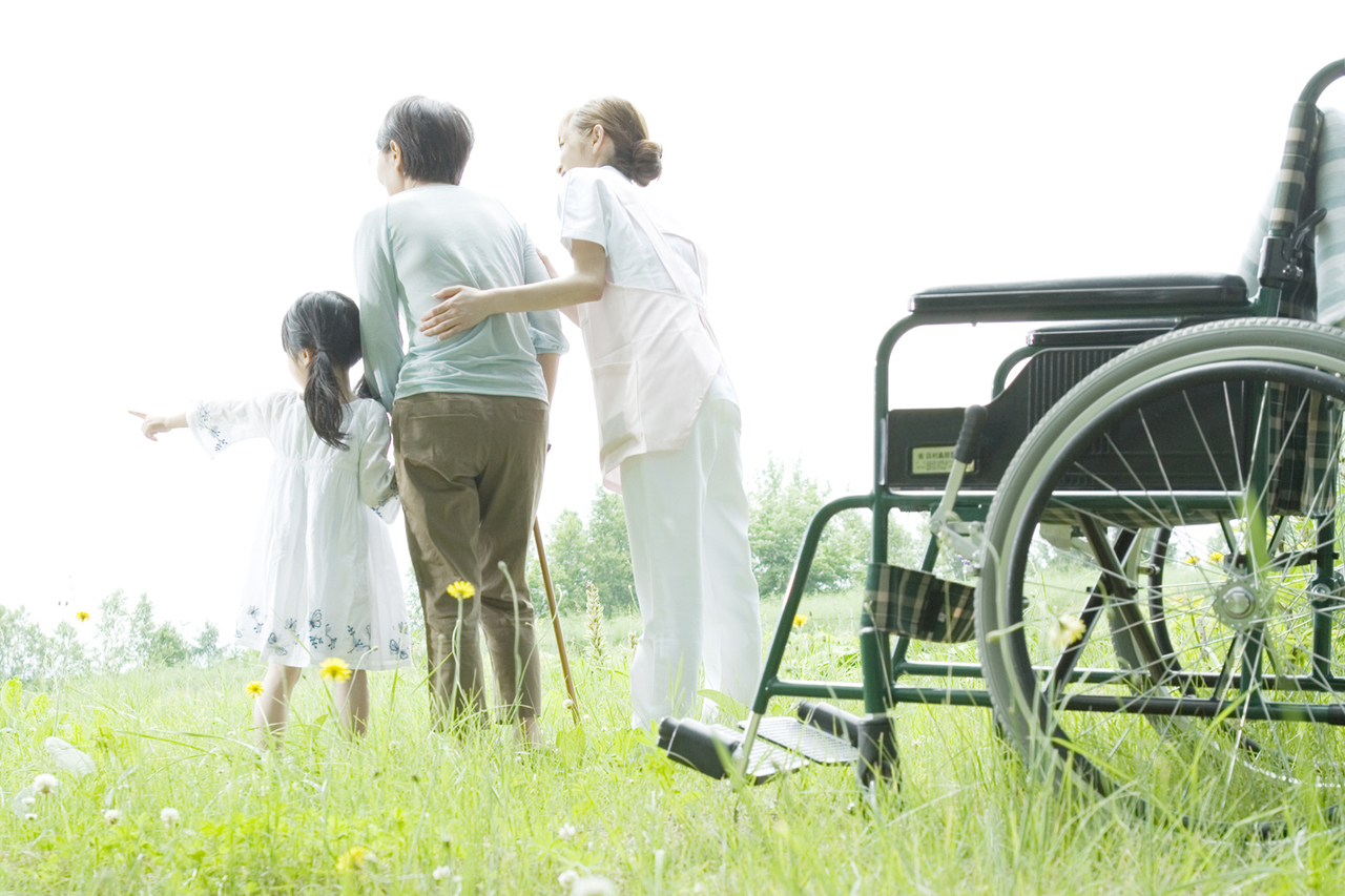 車いすの女性を支える介護士